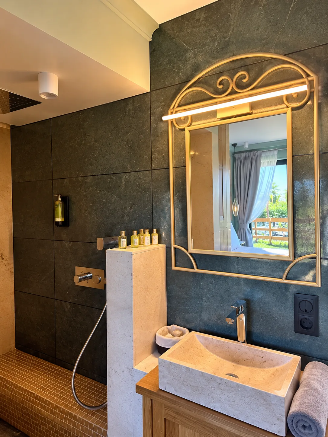 Salle de bains de la Chambre Double Deluxe avec miroir doré et vasque en pierre