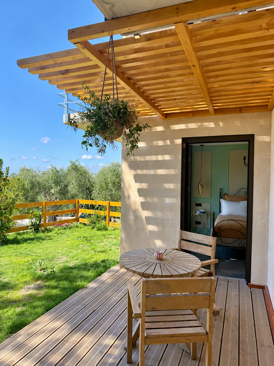 Terrasse privative de la Chambre Double Deluxe, couverte d'une pergola en bois, avec table ronde et chaises