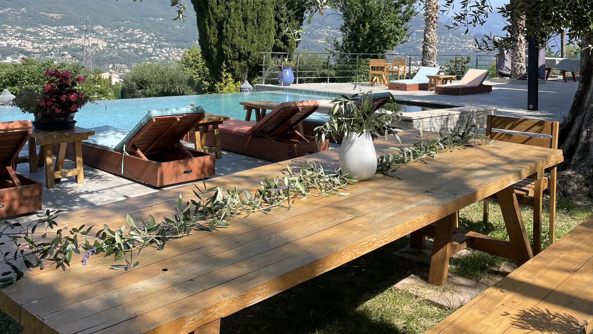Grande table en bois décorée de branches d'olivier, au bord de la piscine de L'Escondida
