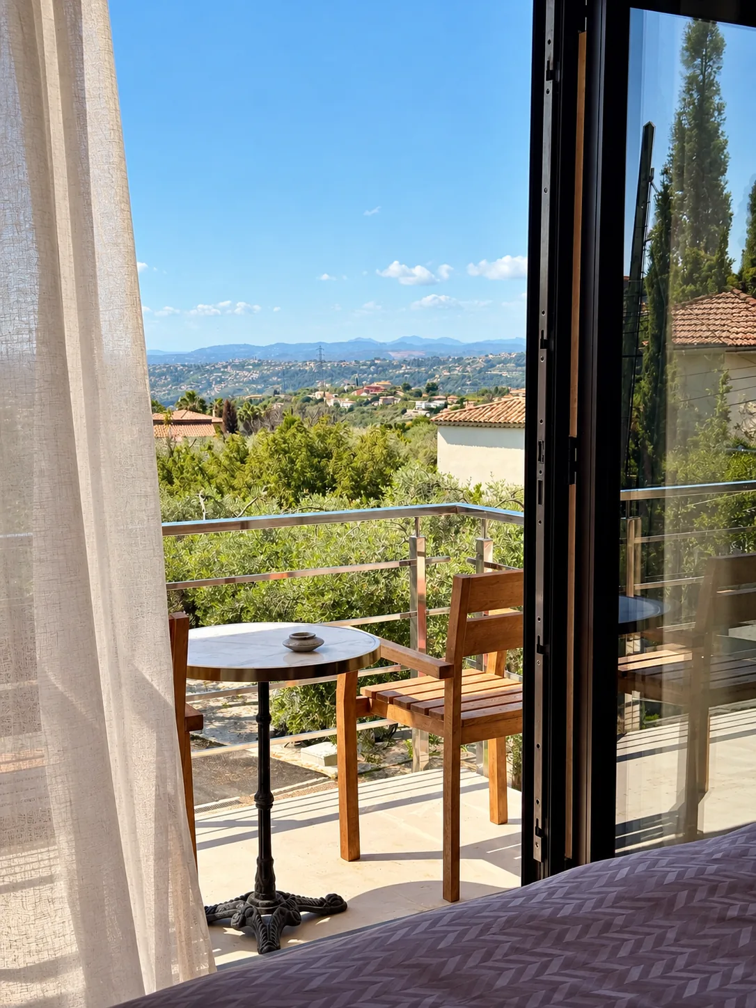 Vue depuis la Suite Deluxe sur les collines et les toits voisins, par la porte-fenêtre ouverte sur le balcon