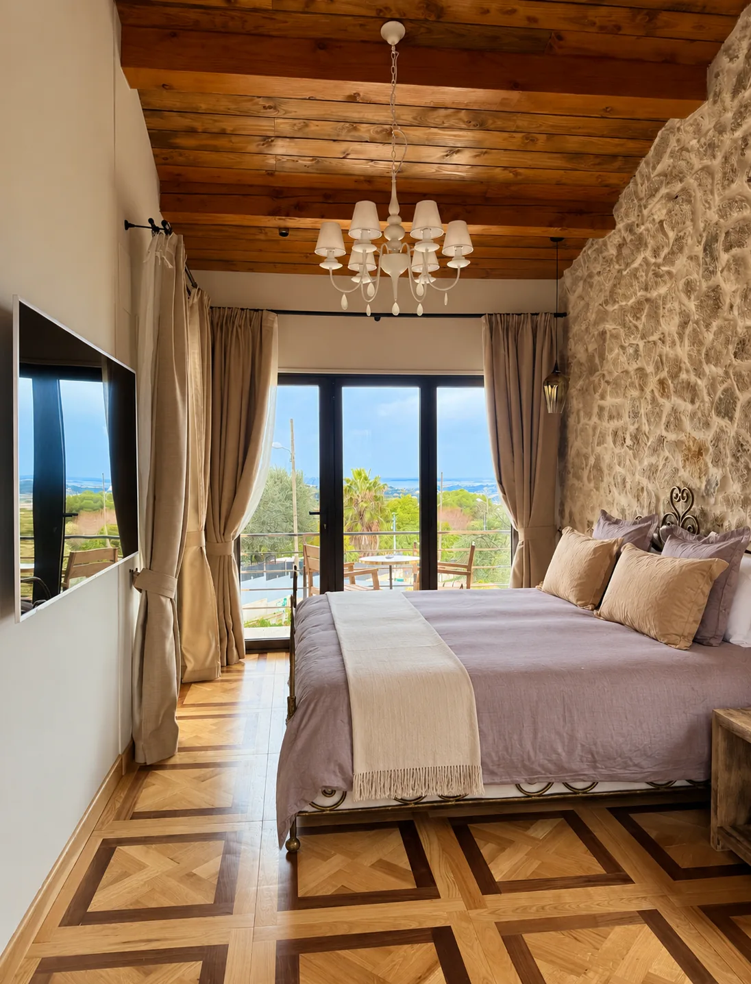 Suite Deluxe aux murs en pierre et plafond en bois, avec baies vitrées ouvrant sur la vue mer